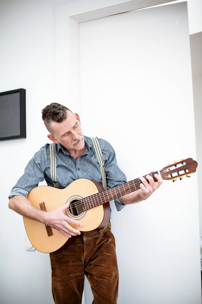 handsome man in his 50s standing and playing guitar - Foto, Bild