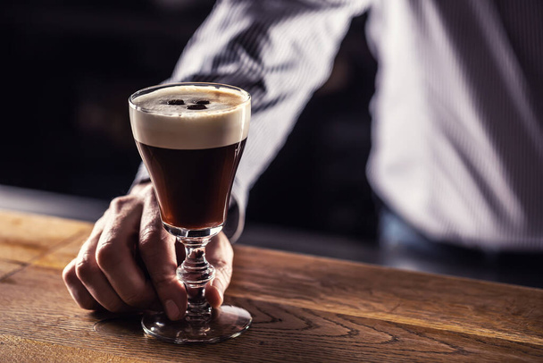 The bartender serves prepared Irish coffee to guests in the cafe. - Photo, image