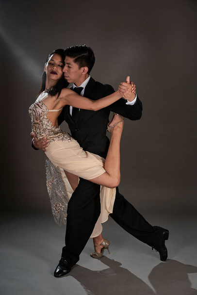 tango ballroom tango couple of latin woman and asian man, studio shot black background - Foto, Imagem
