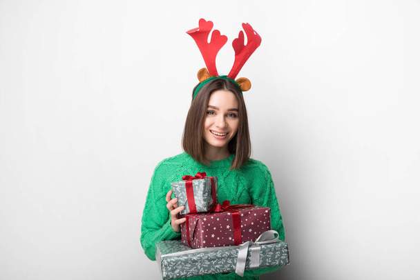 Изолированная молодая улыбающаяся девушка держит красные и зеленые подарки - Фото, изображение