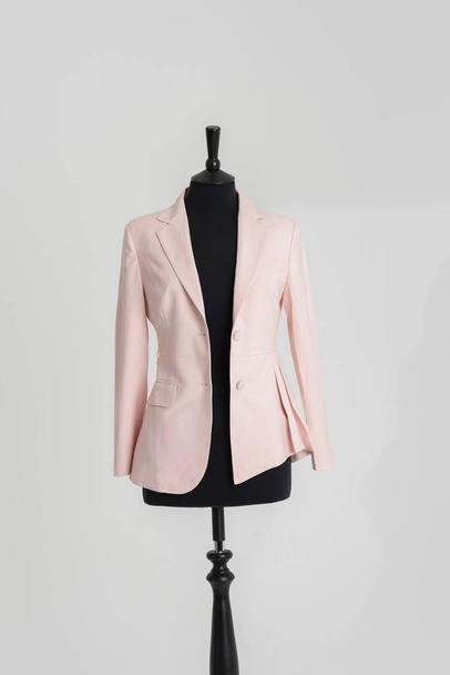 Англия, Великобритания. 2021 год. Женский розовый пиджак висит на портных черный манекен. - Фото, изображение