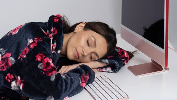 Wiltshire, Regno Unito. 2021. Donna che lavora da casa addormentato dal suo computer desktop e tastiera.  - Foto, immagini