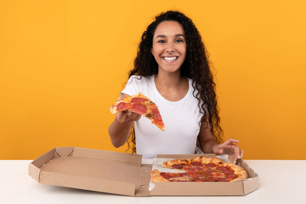 Happy Latin Lady Holding Pizza Offering Slice To Camera - Foto, afbeelding