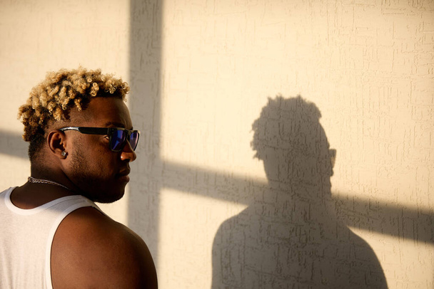 Cool black man in sunglasses and his shadow on the wall - Φωτογραφία, εικόνα