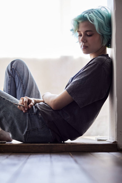 Pensive young woman sit on floor in living room thinking pondering, thoughtful female - Foto, immagini