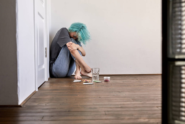 depressed young female sitting on floor and crying, with pills, thinking about suicide - Fotografie, Obrázek