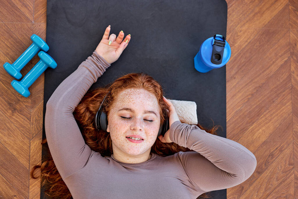Above View On Redhead female listening to music after sport, yoga exercises, relaxation - Photo, Image