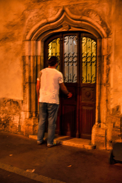 Annecy, France - September 23 2020 : mystic person walking on the street through a medieval historic town with long shadows, buildings, alleys and trying to open a secret door - Zdjęcie, obraz