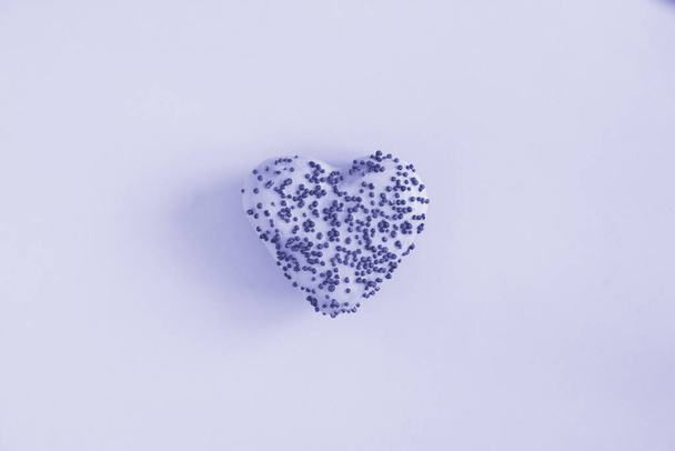Пончик в форме сердца с фиолетовой глазурью на фиолетовом фоне. Концепция нездоровой пищи. Копирование пространства. - Фото, изображение