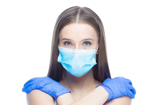 Studio shot on white background of a beautiful young woman wearing mask and latex gloves protected from coronavirus with her hands on naked shoulders stressed by quarantine - Fotó, kép