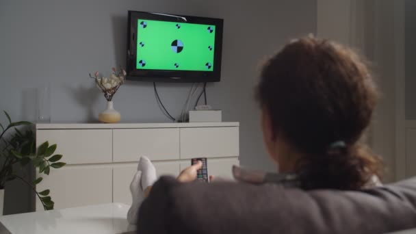 Πλευρική κινούμενη κάμερα, γυναίκα βλέποντας τηλεόραση στο σπίτι, chroma κλειδί πράσινη οθόνη - Πλάνα, βίντεο