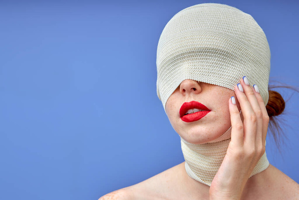 αγνώριστη γυναίκα με μεγάλο κόκκινο χείλος και επίδεσμο στο κεφάλι και το λαιμό μετά από χειρουργική επέμβαση - Φωτογραφία, εικόνα
