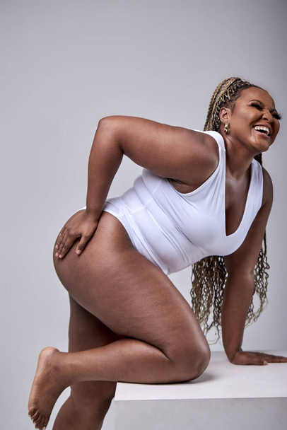 Chubby young woman in white bodysuit posing at camera, on white background - Φωτογραφία, εικόνα