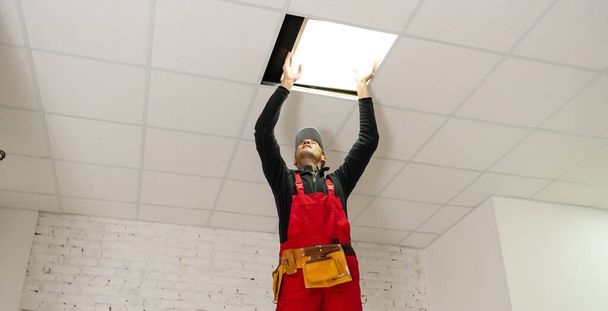 un constructor que reemplaza el panel de techo, de trabajo, armstrong. - Foto, imagen