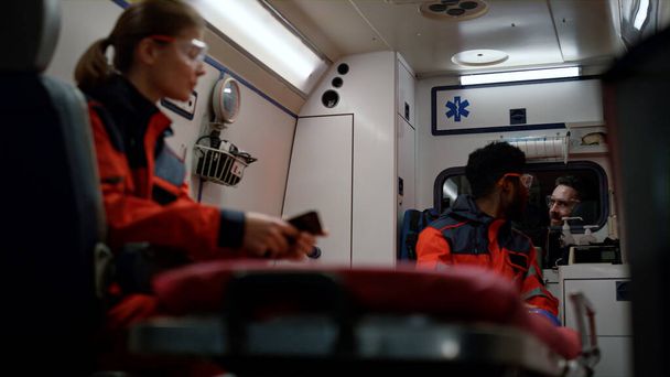 Los paramédicos conducen por accidente en el coche de emergencia. Equipo hablando en furgoneta ambulancia - Foto, imagen