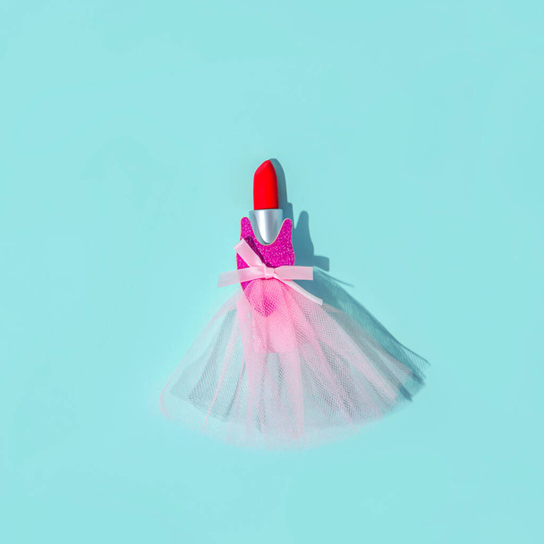 Rouge à lèvres rouge dans une robe de bal. Sur fond bleu-vert. Composition minimale. - Photo, image