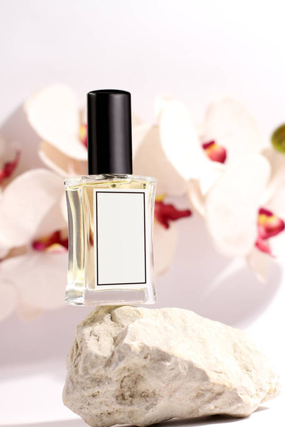 Butelka perfum szklanych w tle kamienia i orchidei, makiety upi - Zdjęcie, obraz