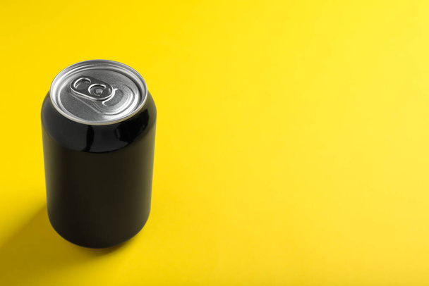 Black can of energy drink on yellow background. Space for text - Fotó, kép