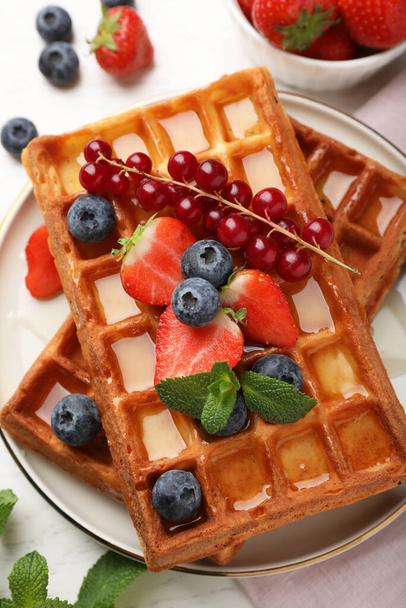 Delicious Belgian waffles with berries served on white table, top view - Foto, imagen
