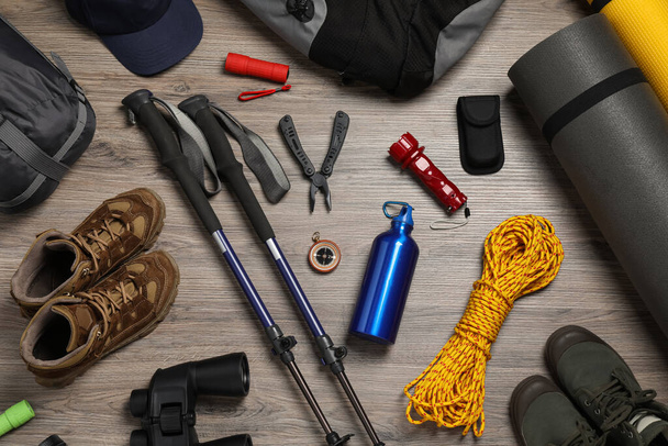 Flat lay composition with trekking poles and other hiking equipment on wooden background - Fotografie, Obrázek