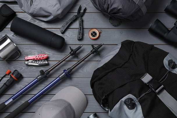 Flat lay composition with trekking poles and other hiking equipment on grey wooden background - Fotoğraf, Görsel