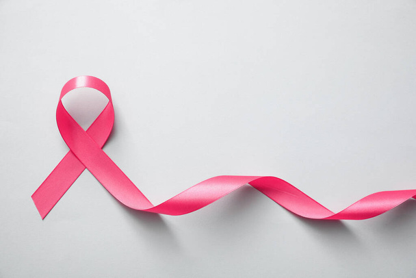 Pink ribbon on light grey background, top view. Breast cancer awareness concept - Фото, изображение