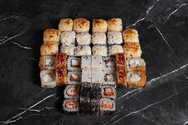 una porzione di diversi rotoli sul tavolo, cibo giapponese, sushi sul marmo, vista dall'alto, bacchette cinesi - Foto, immagini