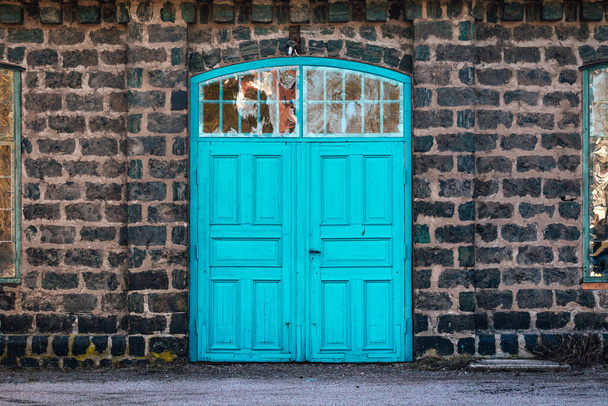Türkiz bejárati ajtó egy nagyon régi acélmalomhoz, ami kőből készült. - Fotó, kép