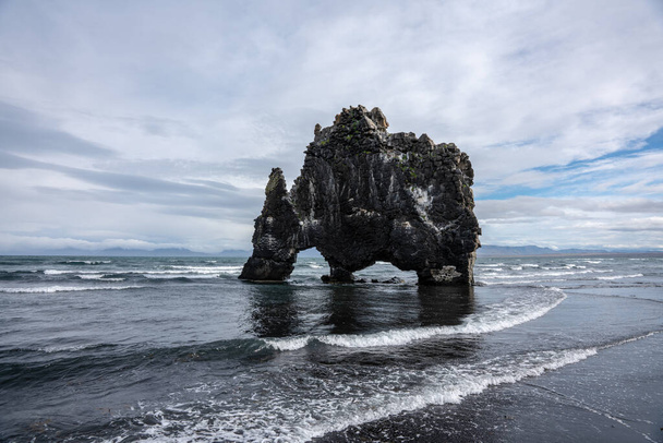 La formazione rocciosa o lavica in piedi nel mare al di fuori della costa settentrionale islandese. Con la forma di un animale, acqua potabile dall'oceano - Foto, immagini