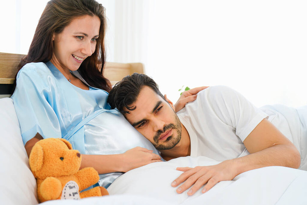 portrait of happy pregnant wife and husband lying together on bed in bed room at home - Foto, immagini