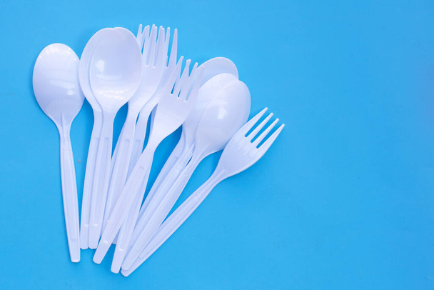 Plastic vork en lepel op blauwe ondergrond. - Foto, afbeelding