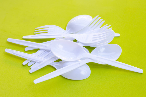 Plastic fork and spoon on green background. - Valokuva, kuva