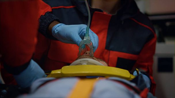 Лікарі швидкої допомоги наносять на людину неінвазивну вентиляційну маску
 - Фото, зображення