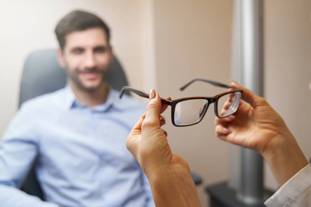 Optometrist bringing pair of glasses to patient - 写真・画像