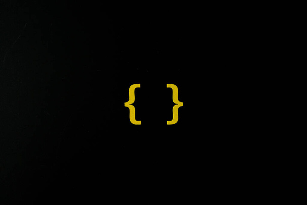 Желтый деревянный символ "кронштейн" на черном фоне и копировальное пространство для образовательной концепции социальных сетей - Фото, изображение