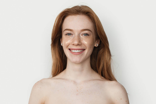 Portret van een blanke vrouw met een perfecte huid geïsoleerd over een witte achtergrond. Mooie Spa Vrouw. Rood haar en sproeten gezicht. - Foto, afbeelding
