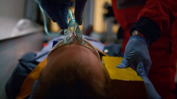 Οι νοσοκόμοι βάζουν μάσκα οξυγόνου στον ασθενή. Βοηθοί ιατρού διασώζουν θύματα - Φωτογραφία, εικόνα