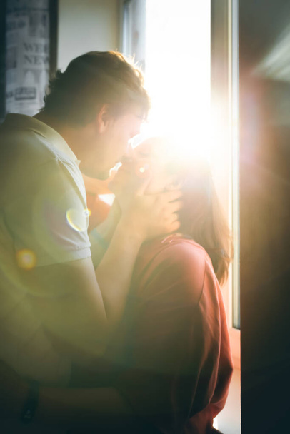 Portrét páru líbajícího se na pozadí západu slunce osvětlujícího kameru. - Fotografie, Obrázek
