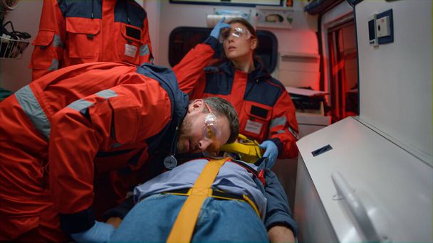Paramedics resuscitating man in car. Medical staff saving life of patient  - Valokuva, kuva