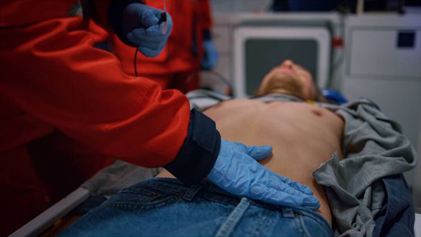 Los paramédicos rescatan al paciente en ambulancia. Los médicos aplican el monitor holter en el hombre - Foto, Imagen