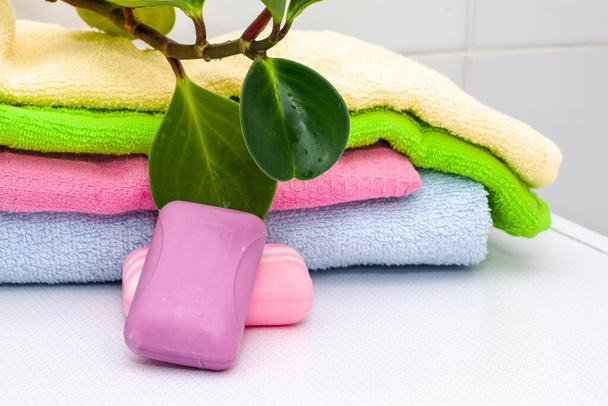 una pila de toallas barras de jabón y una planta de interior en la mesa del baño. Foto de alta calidad - Foto, Imagen