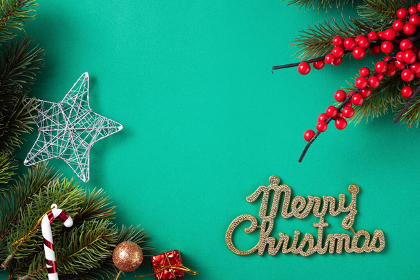 Bovenaanzicht van Kerstmis achtergrond ontwerp concept met dennenboom tak en decoraties op groene tafel achtergrond. - Foto, afbeelding