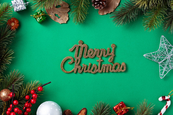 Top view of Christmas background design concept with fir tree branch and decorations on green table background. - 写真・画像