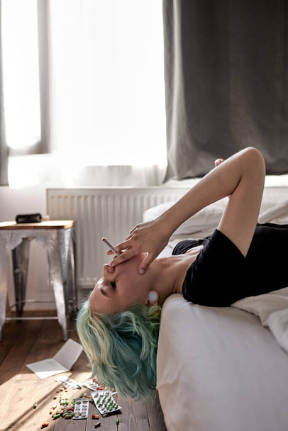 Stressed lady lying on bed at home and crying, smoking. suffering from nervous tension - Fotografie, Obrázek