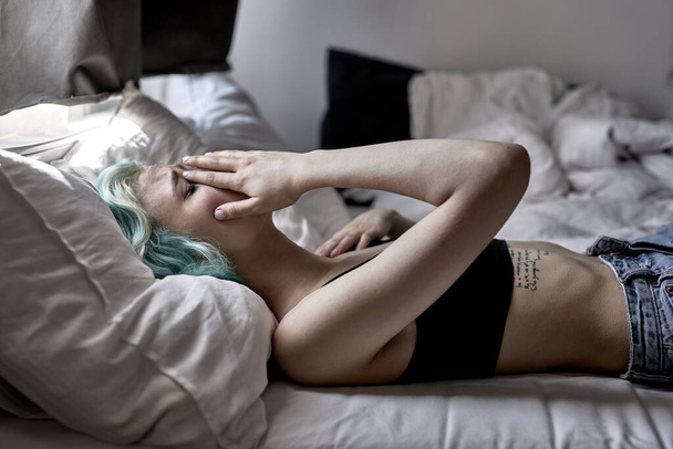 Young beautiful woman with headache on bed, sad, stressed, crying, disappointed feeling - Photo, image