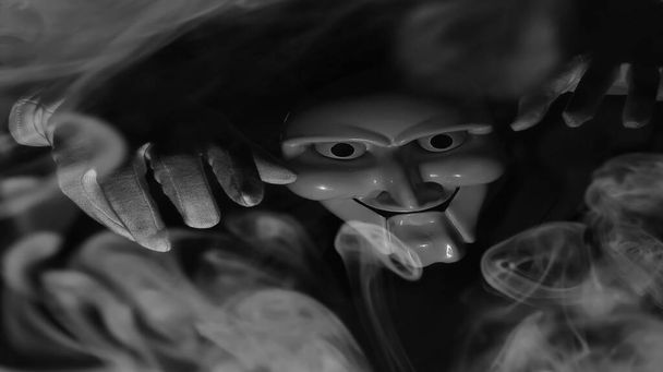 Λευκή τρομακτική μάσκα σε μαύρο φόντο με λευκά χέρια. - Φωτογραφία, εικόνα