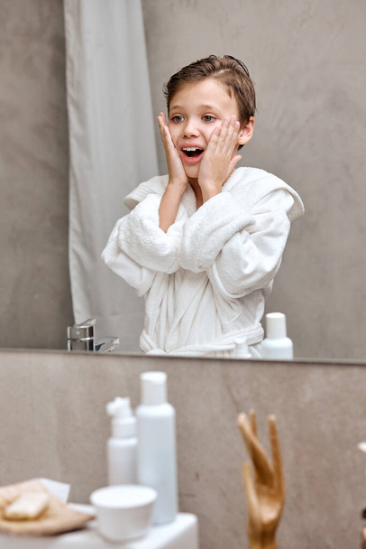 positive school boy applies aftershave like dad in the morning in bath, hygiene at home - Fotoğraf, Görsel