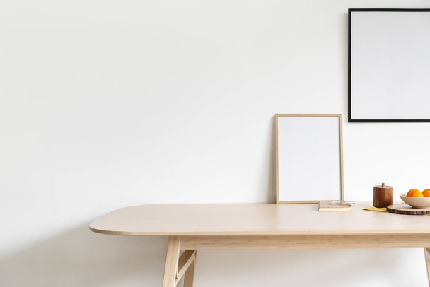 Деревянный обеденный стол с пустыми рамами в светлом помещении - Фото, изображение