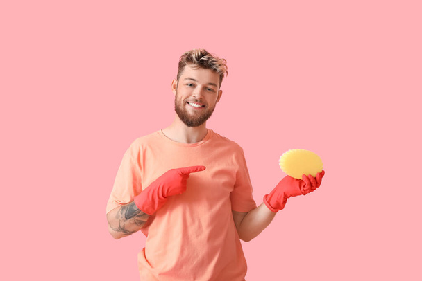 Handsome young man with pointing at sponge on pink background - Photo, Image