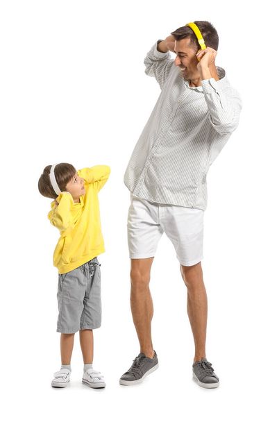 Man and his little son listening to music on white background - Foto, imagen
